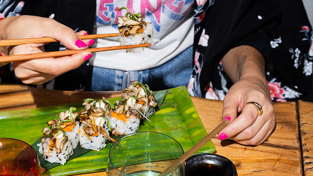 Persona disfrutando sushi vegano durante una cena en Desoriente Barcelona